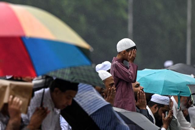 Muslim devotees offer Eid al-Fitr prayers, which marks the end of the Islamic holy fasting month of Ramadan, amid rainfall in Kolkata on March 21, 2026. (Photo by Dibyangshu SARKAR / AFP)