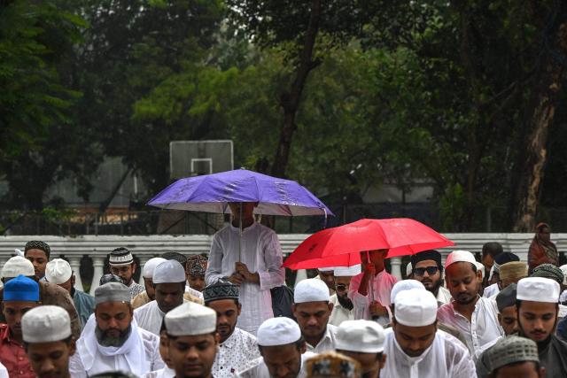Muslim devotees holding umbrellas offer Eid al-Fitr prayers, which marks the end of the Islamic holy fasting month of Ramadan, amid rainfall in Kolkata on March 21, 2026. (Photo by Dibyangshu SARKAR / AFP)