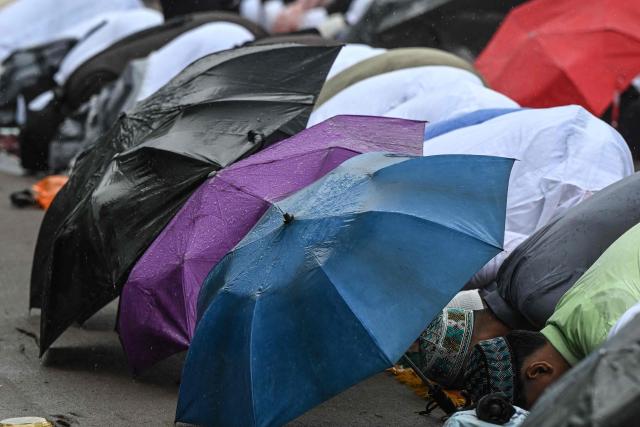 Muslim devotees offer Eid al-Fitr prayers, which marks the end of the Islamic holy fasting month of Ramadan, amid rainfall in Kolkata on March 21, 2026. (Photo by Dibyangshu SARKAR / AFP)