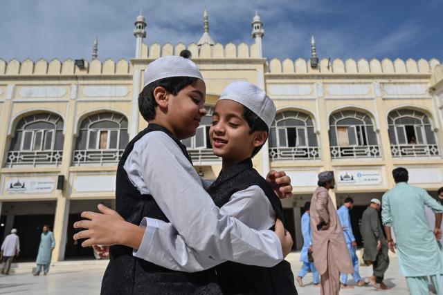 TOPSHOT - Muslim children hug each other after offering Eid al-Fitr prayers, which marks the end of the Islamic holy fasting month of Ramadan, at a mosque in Karachi on March 21, 2026. (Photo by Asif HASSAN / AFP)