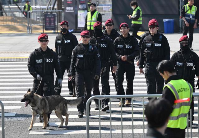 South Korean Police's Special Operations Unit members inspect with a sniffer police dog near the stage of the comeback concert of K-pop boy group BTS at Gwanghwamun Square in downtown Seoul on March 21, 2026. South Korean megastars BTS reunite on March 21, for their first show in nearly four years, with an expected 260,000 fans taking over central Seoul for a K-pop extravaganza livestreamed to millions more worldwide. (Photo by Jung Yeon-je / AFP)