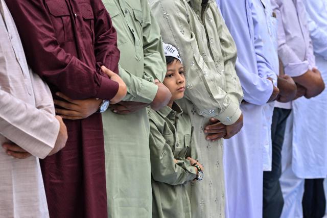 A Muslim boy along with other devotees offers Eid al-Fitr prayers, which marks the end of the Islamic holy fasting month of Ramadan, at the Idgah field in Guwahati on March 21, 2026. (Photo by Biju BORO / AFP)