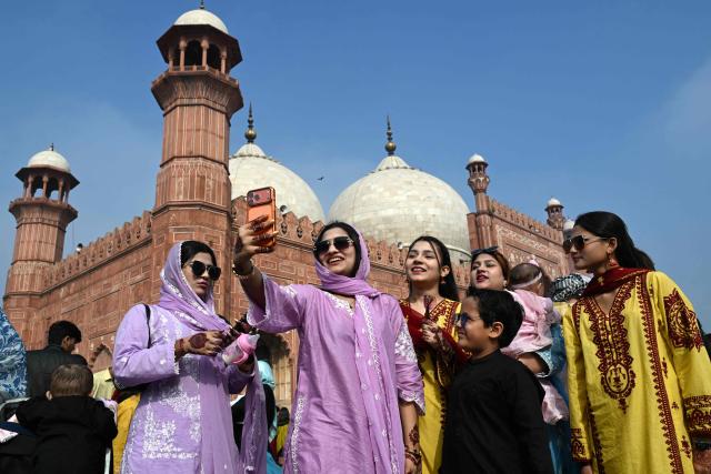 Muslims pose for a selfie after offering Eid al-Fitr prayers, which marks the end of the Islamic holy fasting month of Ramadan, at the Badshahi Mosque in Lahore on March 21, 2026. (Photo by Arif ALI / AFP)