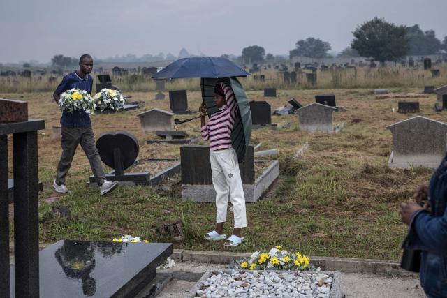 A girl shields from the rain as a member of the protocol carries flowers to the graves of the dozens killed on March 21, 1960 during what is remembered as the Sharpeville Massacre, at the Phelindaba Cemetery in Sharpeville, on March 21, 2026. The Sharpeville massacre occurred on 21 March 1960, when police opened fire on a crowd of people who had assembled outside the police station in the township of Sharpeville in the then Transvaal Province of the then Union of South Africa (today part of Gauteng) to protest against the pass laws. Today South Africa remembers the victims in what has become Human Rights Day. (Photo by MARCO LONGARI / AFP)