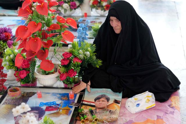 An Iraqi Shia visits a grave at the pro-Iranian armed group Kataeb Hezbollah Cemetery in Iraq's central holy city of Najaf as they remember the deceased as well as victims of wars on Eid al-Fitr, marking the end of the fasting month of Ramadan, on March 21, 2026. Iraq has been unwillingly drawn into the regional conflict triggered by the US-Israel attack on its neighbour Iran on February 28. Strikes have targeted Iran-backed groups, which in turn have claimed near-daily attacks on US interests, mostly in Iraq but also across the wider region. (Photo by AFP)