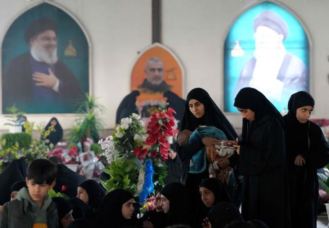 Iraqi Shias visit graves of relatives at the pro-Iranian armed group Kataeb Hezbollah Cemetery in Iraq's central holy city of Najaf as they remember the deceased as well as victims of wars on Eid al-Fitr, marking the end of the fasting month of Ramadan, on March 21, 2026. Iraq has been unwillingly drawn into the regional conflict triggered by the US-Israel attack on its neighbour Iran on February 28. Strikes have targeted Iran-backed groups, which in turn have claimed near-daily attacks on US interests, mostly in Iraq but also across the wider region. (Photo by AFP)