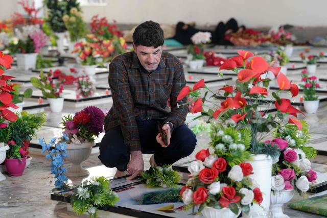 An Iraqi Shia visits a grave at the pro-Iranian armed group Kataeb Hezbollah Cemetery in Iraq's central holy city of Najaf as they remember the deceased as well as victims of wars on Eid al-Fitr, marking the end of the fasting month of Ramadan, on March 21, 2026. Iraq has been unwillingly drawn into the regional conflict triggered by the US-Israel attack on its neighbour Iran on February 28. Strikes have targeted Iran-backed groups, which in turn have claimed near-daily attacks on US interests, mostly in Iraq but also across the wider region. (Photo by AFP)