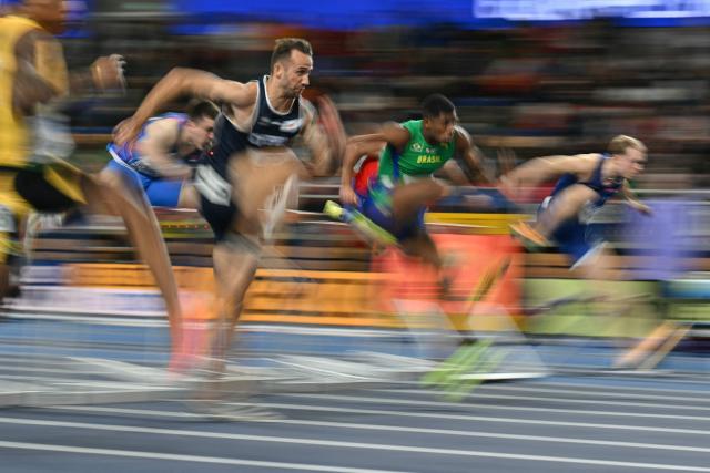 This slow shutter photograph shows athletes including Cyprus' Milan Trajkovic (Centre L), Brazil's Thiago Resende Ornelas Dos Santos and Finland's Santeri Kuusiniemi competing in the men's 60 metres hurdles heat 4 during the World Athletics Indoor Championships Kujawy Pomorze 2026 in Torun, Poland on March 21, 2026. (Photo by Andrej ISAKOVIC / AFP)
