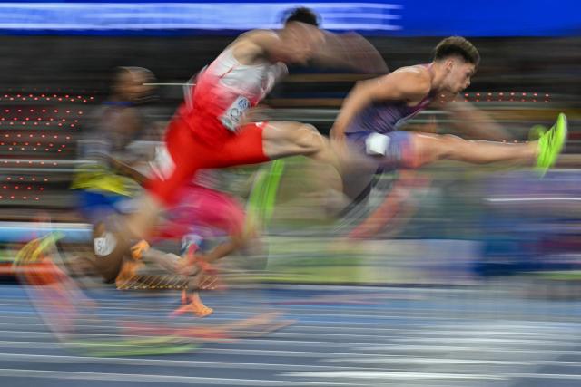 This slow shutter photograph shows athletes including Poland's Damian Czykier (C) and USA's Trey Cunningham competing in the men's 60 metres hurdles heat 6 during the World Athletics Indoor Championships Kujawy Pomorze 2026 in Torun, Poland on March 21, 2026. (Photo by Andrej ISAKOVIC / AFP)