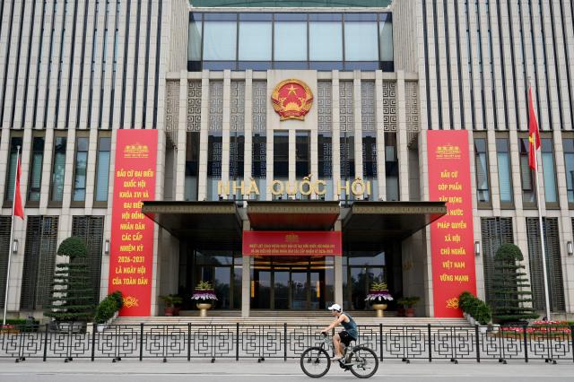A man rides a bicycle past the National Assembly Building in Hanoi on March 21, 2026. (Photo by Nhac NGUYEN / AFP)