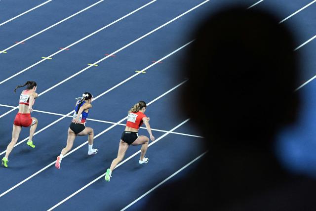 A spectator watches as (LtoR) Canada's Audrey Leduc, Philippines' Jessica Laurance and Switzerland's Léonie Pointet compete in the women's 60 metres heat 1 during the World Athletics Indoor Championships Kujawy Pomorze 2026 in Torun, Poland on March 21, 2026. (Photo by Kirill KUDRYAVTSEV / AFP)