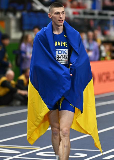 Ukraine's Oleh Doroshchuk celebrates with his country's flag winning the Men's High Jump final during the World Athletics Indoor Championships Kujawy Pomorze 2026 in Torun, Poland on March 21, 2026. (Photo by Andrej ISAKOVIC / AFP)