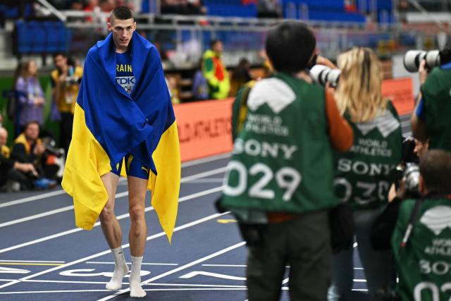 Ukraine's Oleh Doroshchuk celebrates with his country's flag winning the Men's High Jump final during the World Athletics Indoor Championships Kujawy Pomorze 2026 in Torun, Poland on March 21, 2026. (Photo by Andrej ISAKOVIC / AFP)