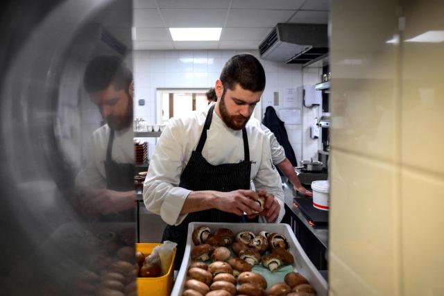 A cook prepares mushrooms in the kitchen at the restaurant Les Morainieres, whose French chef Michael Arnoult has just been awarded a third Michelin star, in Jongieux, central-eastern France, on March 20, 2026. The calm amid the vineyards of Jongieux in Savoie contrasts with the bustle of the restaurant Les Morainières, where chef Michael Arnoult received no fewer than 250 reservations as soon as his third Michelin star was awarded. (Photo by OLIVIER CHASSIGNOLE / AFP)