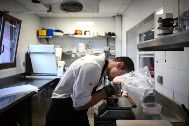 A cook works in the kitchen at the restaurant Les Morainieres, whose French chef Michael Arnoult has just been awarded a third Michelin star, in Jongieux, central-eastern France, on March 20, 2026. The calm amid the vineyards of Jongieux in Savoie contrasts with the bustle of the restaurant Les Morainières, where chef Michael Arnoult received no fewer than 250 reservations as soon as his third Michelin star was awarded. (Photo by OLIVIER CHASSIGNOLE / AFP)