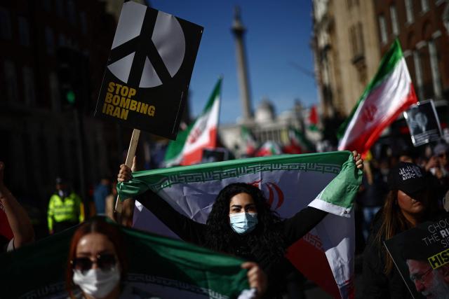 Protesters carry placards and wave Iranian flags on Whitehall during of a protest march in central London on March 21, 2026, calling for the bombing of Iran to stop. Britain has authorised the United States to use its bases to strike Iranian sites threatening the Strait of Hormuz shipping lane, the government said Friday. (Photo by Henry NICHOLLS / AFP)