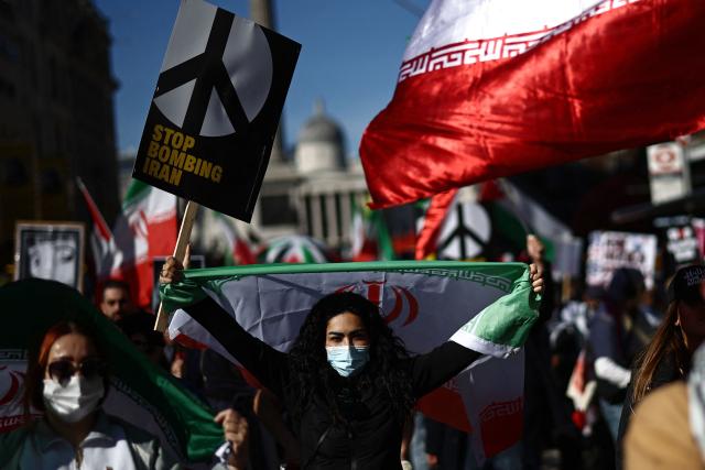 Protesters carry placards and wave Iranian flags on Whitehall during of a protest march in central London on March 21, 2026, calling for the bombing of Iran to stop. Britain has authorised the United States to use its bases to strike Iranian sites threatening the Strait of Hormuz shipping lane, the government said Friday. (Photo by Henry NICHOLLS / AFP)