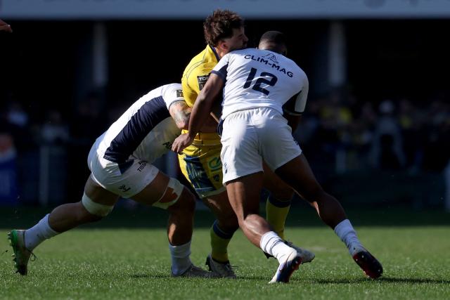 Clermont's New Zelander Harry Plummer (C) is tackled by Montpellier’s English centre Lennox Anyanwu during the French Top14 rugby union match between ASM Clermont Auvergne and Montpellier Herault Rugby at the Stade Marcel-Michelin in Clermont-Ferrand, central France on March 21, 2026. (Photo by Alex MARTIN / AFP)