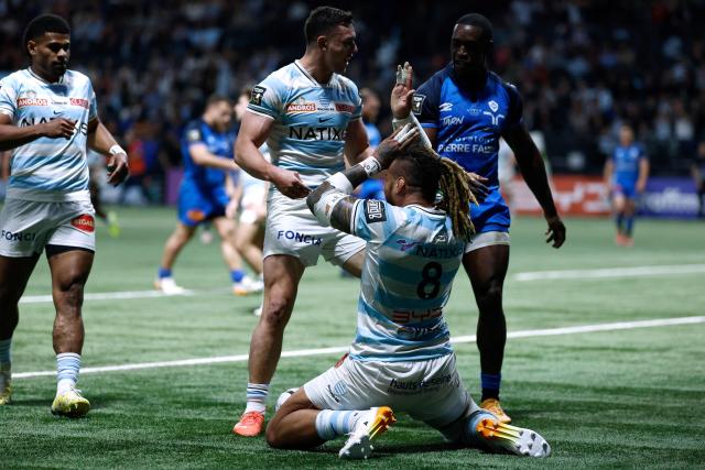 Racing 92' Fijian number 8 Nathan Hughes (C) celebrates with teammates after scoring try during the French Top 14 rugby union match between Racing 92 and Castres Olympique at the Paris La Défense Arena in Nanterre, on March 21, 2026. (Photo by Kenzo TRIBOUILLARD / AFP)