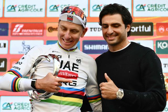 UAE Team Emirate's Slovenian rider Tadej Pogacar, winner, is congratulated by Spanish F1 driver Carlos Sainz as he celebrates on the podium of the 117th Milan - Sanremo one-day classic cycling race, in Sanremo on March 21, 2026. (Photo by Marco BERTORELLO / AFP)