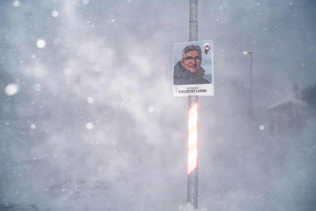 This image shows a poster of a candidate from the Greenlandic Social Democratic party Inuit Ataqatigiit, plastered on a pole during a snowstorm, in Nuuk, Greenland, on March 21, 2026. As early legislative elections are being held in Denmark on March 24, Greenland will also have to vote to elect two representatives to the Danish parliament. (Photo by Florent VERGNES / AFP)