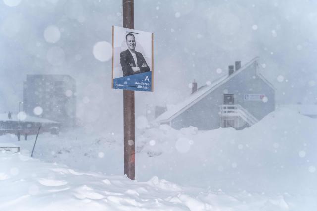 This image shows a poster of a candidate from the Greenlandic liberal-conservative and unionist political party Atassut, plastered on a pole during a snowstorm, in Nuuk, Greenland, on March 21, 2026. As early legislative elections are being held in Denmark on March 24, Greenland will also have to vote to elect two representatives to the Danish parliament. (Photo by Florent VERGNES / AFP)