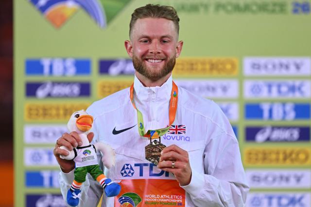 Britain's Josh Kerr celebrates with his gold medal on the podium for the men's 3000 metres event during the World Athletics Indoor Championships Kujawy Pomorze 2026 in Torun, Poland on March 21, 2026. (Photo by Andrej ISAKOVIC / AFP)