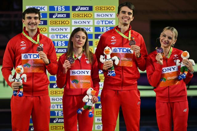 Bronze medallists Poland's Marcin Karolewski (L), Poland's Anna Gryc, Poland's Kajetan Duszynski and Poland's Justyna Swiety-Ersetic celebrate on the podium for the 4x400 relay during the World Athletics Indoor Championships Kujawy Pomorze 2026 in Torun, Poland on March 21, 2026. (Photo by Andrej ISAKOVIC / AFP)