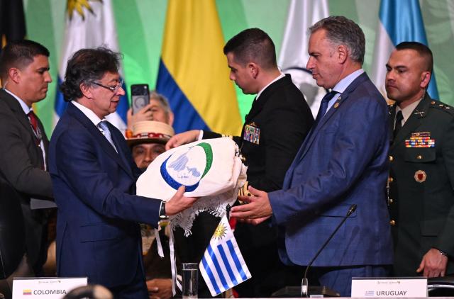 Colombia's President Gustavo Petro (L) hands over the pro tempore presidency to Uruguay's President Yamandu Orsi during the X Summit of Heads of State and Government, within the framework of the CELAC-Africa High-Level Forum, in Bogota on March 21, 2026. (Photo by Raul ARBOLEDA / AFP)