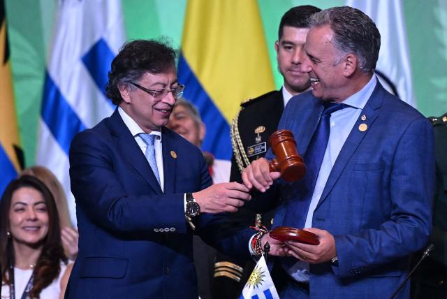 Colombia's President Gustavo Petro (L) hands over the pro tempore presidency to Uruguay's President Yamandu Orsi during the X Summit of Heads of State and Government, within the framework of the CELAC-Africa High-Level Forum, in Bogota on March 21, 2026. (Photo by Raul ARBOLEDA / AFP)