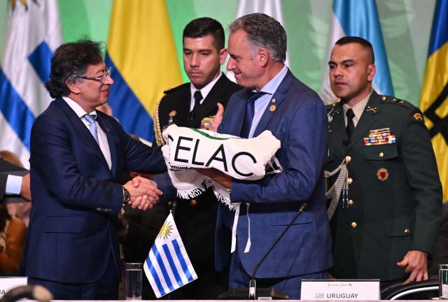 Colombia's President Gustavo Petro (L) hands over the pro tempore presidency to Uruguay's President Yamandu Orsi during the X Summit of Heads of State and Government, within the framework of the CELAC-Africa High-Level Forum, in Bogota on March 21, 2026. (Photo by Raul ARBOLEDA / AFP)