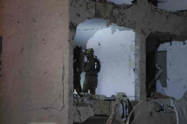 First responders inspect the site of an Iranian missile strike in Arad early on March 22, 2026. Israeli medics said 59 people were wounded in an Iranian missile strike March 21 on the southern town of Arad, raising initial casualty figures. (Photo by Ilia YEFIMOVICH / AFP) / 