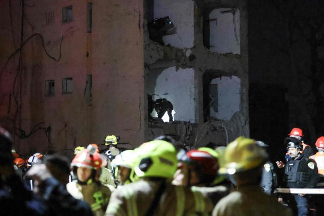 First responders inspect the site of an Iranian missile strike in Arad early on March 22, 2026. Israeli medics said 59 people were wounded in an Iranian missile strike March 21 on the southern town of Arad, raising initial casualty figures. (Photo by Ilia YEFIMOVICH / AFP) / 
