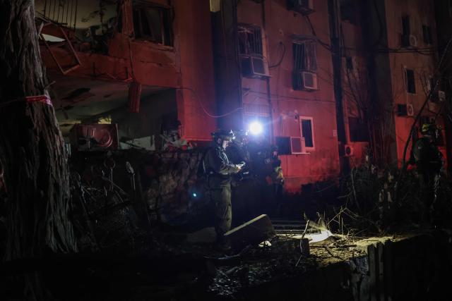 TOPSHOT - First responders inspect the site of an Iranian missile strike in Arad early on March 22, 2026. Iranian missile strikes on two southern Israeli towns wounded more than 100 people on March 21, medics said, after Israeli air defence systems failed to intercept the projectiles. (Photo by Ilia YEFIMOVICH / AFP) / 
