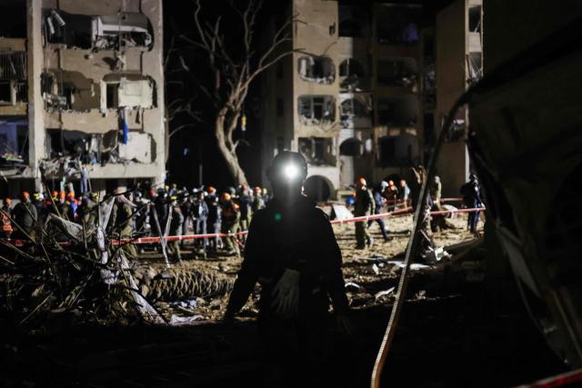 TOPSHOT - First responders inspect the site of an Iranian missile strike in Arad early on March 22, 2026. Iranian missile strikes on two southern Israeli towns wounded more than 100 people on March 21, medics said, after Israeli air defence systems failed to intercept the projectiles. (Photo by Ilia YEFIMOVICH / AFP) / 