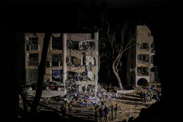 TOPSHOT - First responders inspect the site of an Iranian missile strike in Arad early on March 22, 2026. Iranian missile strikes on two southern Israeli towns wounded more than 100 people on March 21, medics said, after Israeli air defence systems failed to intercept the projectiles. (Photo by Ilia YEFIMOVICH / AFP) / 
