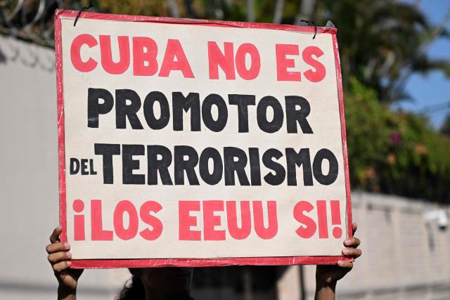 A woman holds as sign that reads 'Cuba is not a terrorism promoter, US is' during a demonstration in solidarity with Cuba and against the US embargo, under the slogan “Cuba is not a threat,” outside the Cuban embassy in San Salvador on March 21, 2026. (Photo by Marvin RECINOS / AFP)