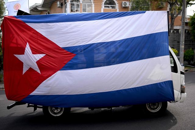 A truck covered with a Cuban flag is pictured during a demonstration in solidarity with Cuba and against the US embargo, under the slogan “Cuba is not a threat,” outside the Cuban embassy in San Salvador on March 21, 2026. (Photo by Marvin RECINOS / AFP)