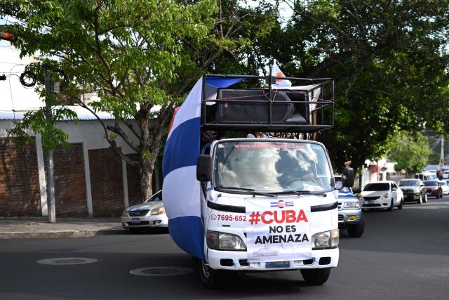 A truck covered with a Cuban flag and with a sign that reads 'Cuba is not a threat' is pictured during a demonstration in solidarity with Cuba and against the US embargo, under the slogan “Cuba is not a threat,” outside the Cuban embassy in San Salvador on March 21, 2026. (Photo by Marvin RECINOS / AFP)