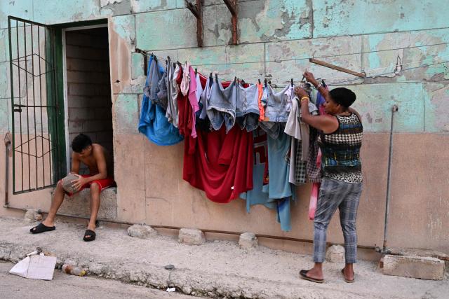 A woman hang clothes to dry during a nation wide blackout in Havana on March 21, 2026. A power outage struck the entire island of Cuba on March 21, 2026, the energy ministry said, in the second nationwide blackout in less than a week as its grid struggles under a US oil blockade. (Photo by Yamil LAGE / AFP)