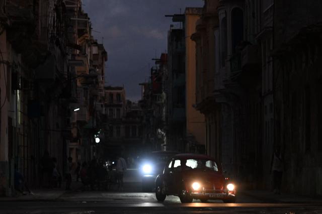 People transit on a street without power during a nation wide blackout in Havana on March 21, 2026. A power outage struck the entire island of Cuba on March 21, 2026, the energy ministry said, in the second nationwide blackout in less than a week as its grid struggles under a US oil blockade. (Photo by Yamil LAGE / AFP)