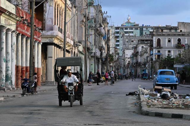 People transit on a street without power during a nation wide blackout in Havana on March 21, 2026. A power outage struck the entire island of Cuba on March 21, 2026, the energy ministry said, in the second nationwide blackout in less than a week as its grid struggles under a US oil blockade. (Photo by Yamil LAGE / AFP)