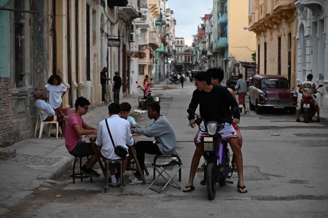 Cubans play domino on a street without power during a nation wide blackout in Havana on March 21, 2026. A power outage struck the entire island of Cuba on March 21, 2026, the energy ministry said, in the second nationwide blackout in less than a week as its grid struggles under a US oil blockade. (Photo by Yamil LAGE / AFP)