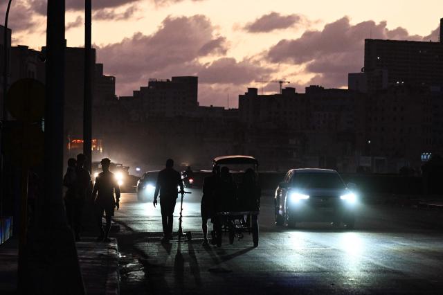 People transit on a street without power during a nation wide blackout in Havana on March 21, 2026. A power outage struck the entire island of Cuba on March 21, 2026, the energy ministry said, in the second nationwide blackout in less than a week as its grid struggles under a US oil blockade. (Photo by Yamil LAGE / AFP)
