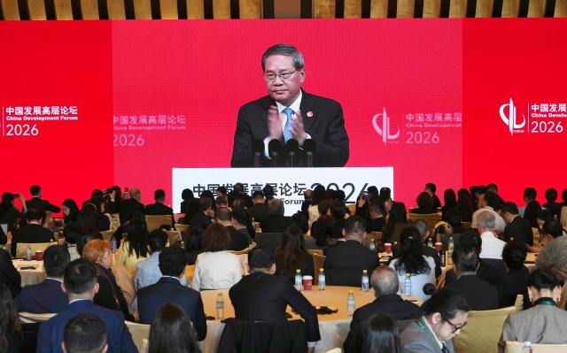 Chinese Premier Li Qiang is seen on a big screen live broadcasting his speech at the opening of the China Development Forum 2026 held at the Diaoyutai State Guesthouse in Beijing on March 22, 2026. (Photo by Ng Han Guan / POOL / AFP)