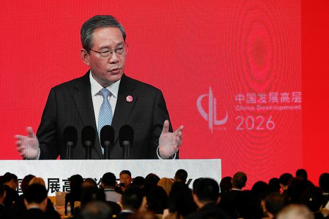 Chinese Premier Li Qiang is seen on a big screen live broadcasting his speech at the opening of the China Development Forum 2026 held at the Diaoyutai State Guesthouse in Beijing on March 22, 2026. (Photo by Ng Han Guan / POOL / AFP)