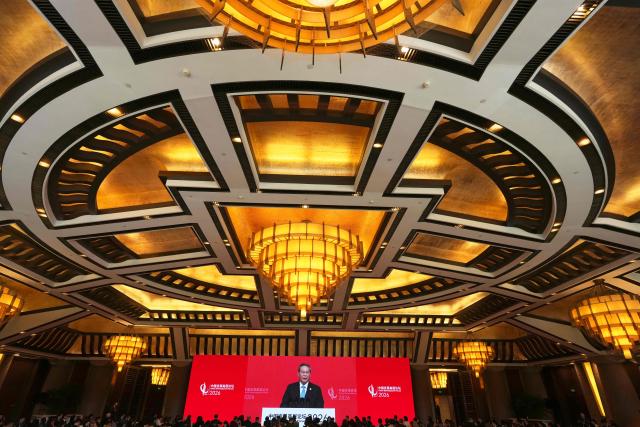 Chinese Premier Li Qiang is seen on a big screen live broadcasting his speech at the opening of the China Development Forum 2026 held at the Diaoyutai State Guesthouse in Beijing on March 22, 2026. (Photo by Ng Han Guan / POOL / AFP)