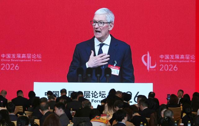 Apple CEO Tim Cook is seen on a big screen live broadcasting his speech at the opening of the China Development Forum 2026 held at the Diaoyutai State Guesthouse in Beijing on March 22, 2026. (Photo by Ng Han Guan / POOL / AFP)