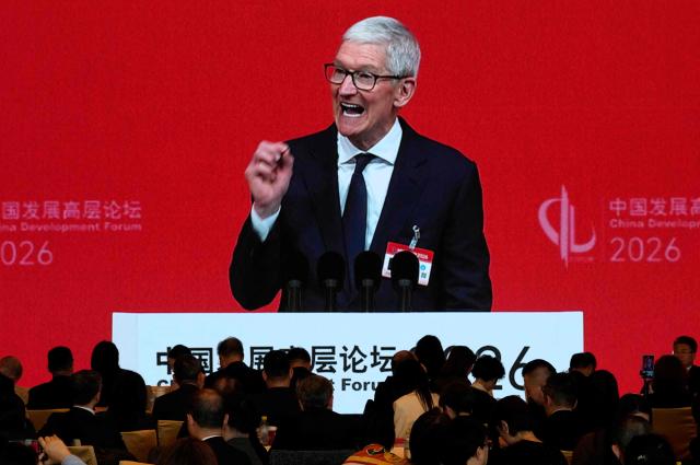 Apple CEO Tim Cook is seen on a big screen live broadcasting his speech at the opening of the China Development Forum 2026 held at the Diaoyutai State Guesthouse in Beijing on March 22, 2026. (Photo by Ng Han Guan / POOL / AFP)