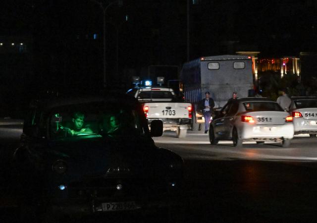 people transit on a street without power during a nation wide blackout in Havana on March 21, 2026. A power outage struck the entire island of Cuba on March 21, 2026, the energy ministry said, in the second nationwide blackout in less than a week as its grid struggles under a US oil blockade. (Photo by Yamil LAGE / AFP)